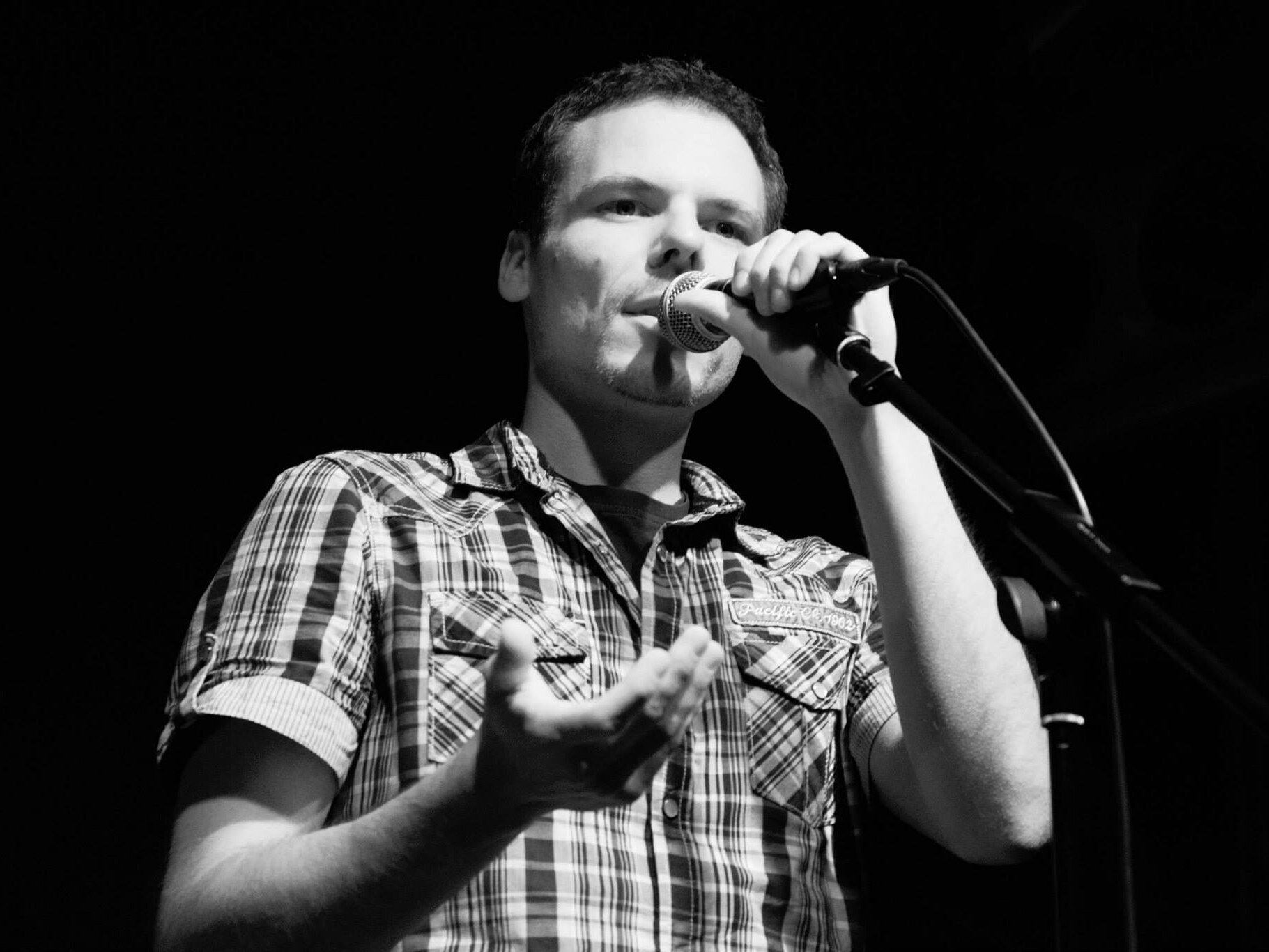 Ein schwarzweiß-Fotografie von mir mit Mikrofon während eines Auftritts