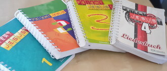 Die Feiert-Jesus-Ringbücher Band 1-4 liegen locker gestapelt im Halbkreis auf einem Tisch